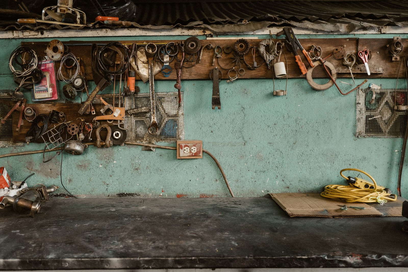 A workshop bench under a tool wall, the mint-green plaster hung with clips, wire and fittings