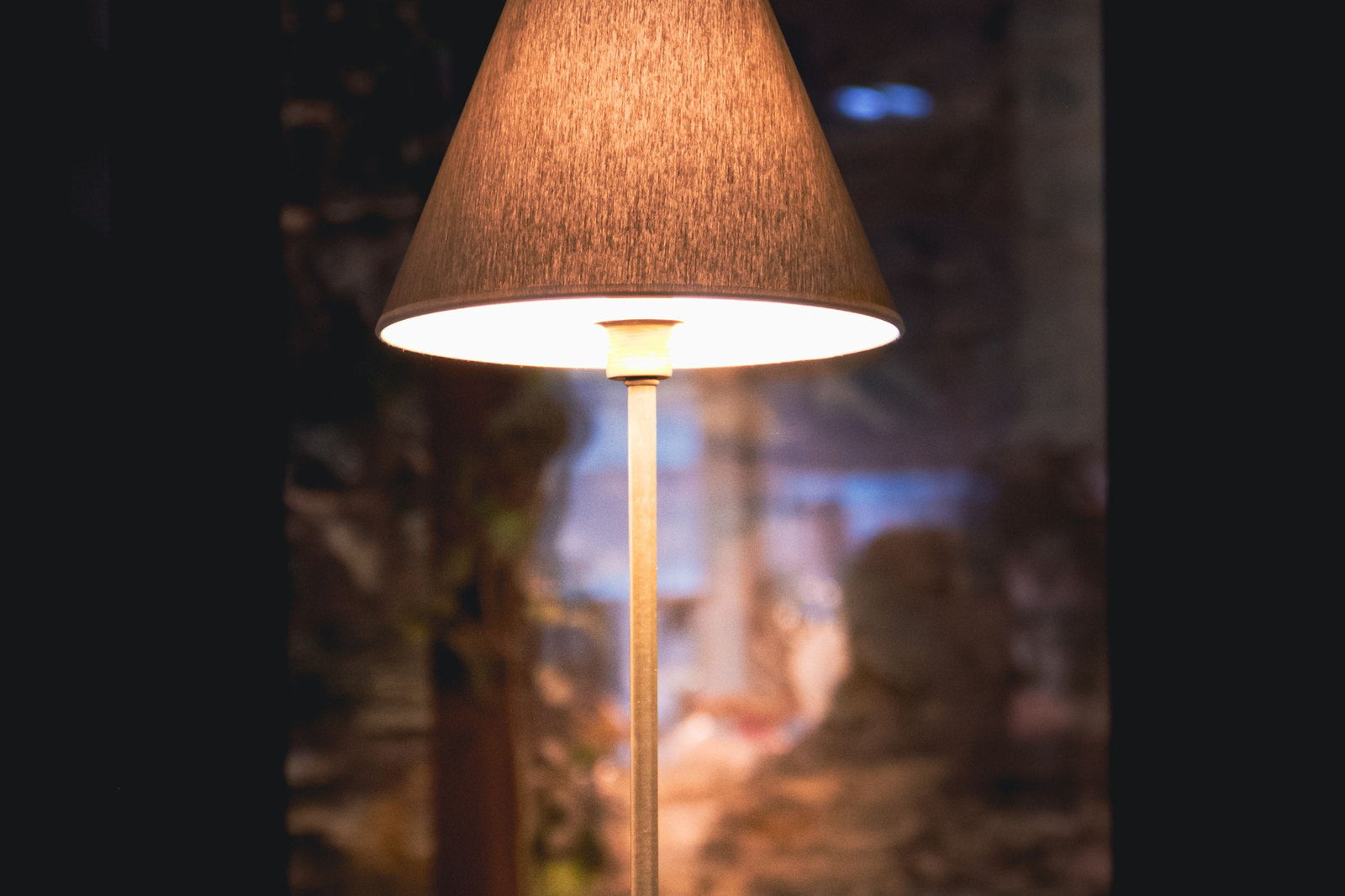 A desk lamp lit over a working desk after dark, the room behind it unlit