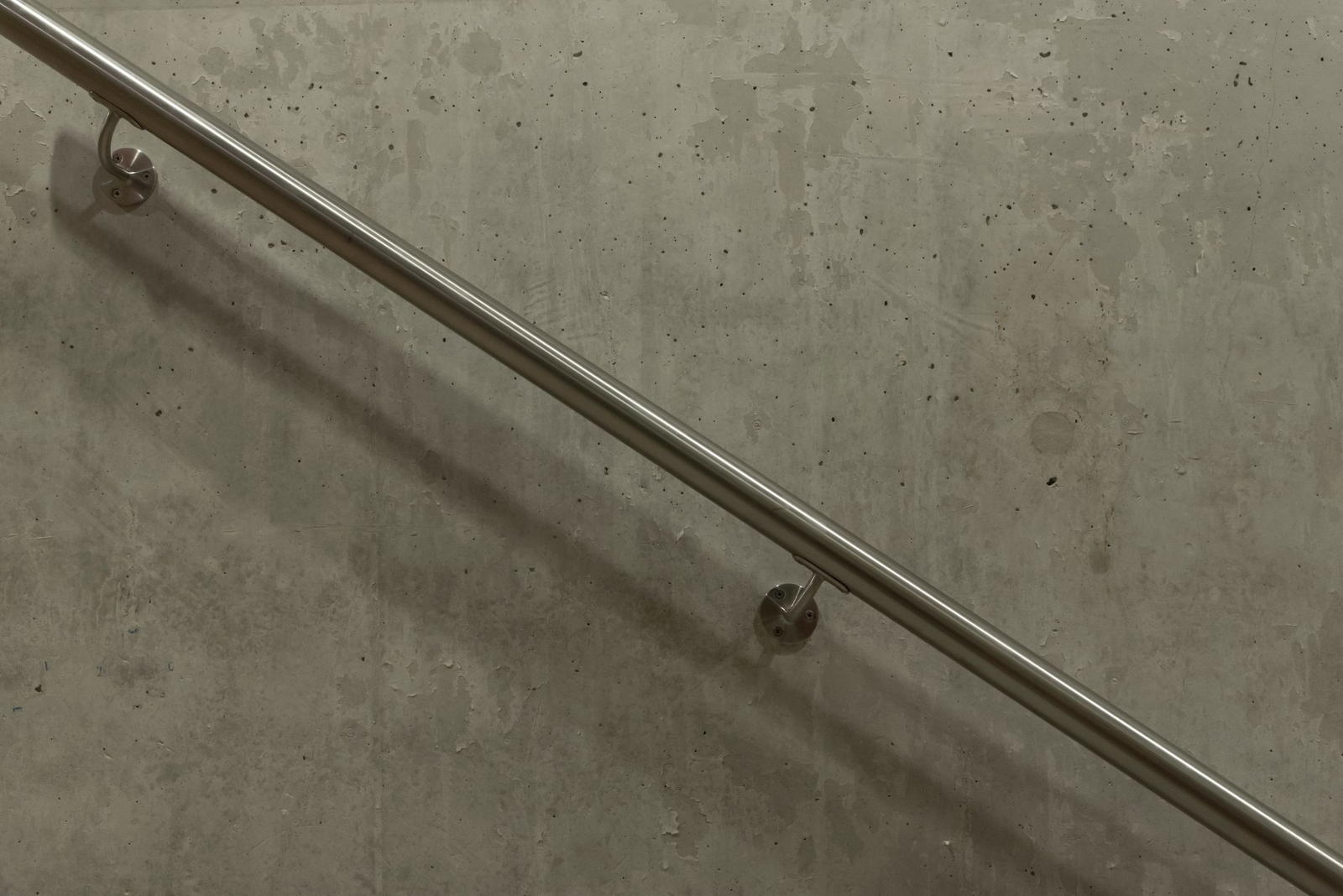 A stainless handrail running diagonally across a concrete wall