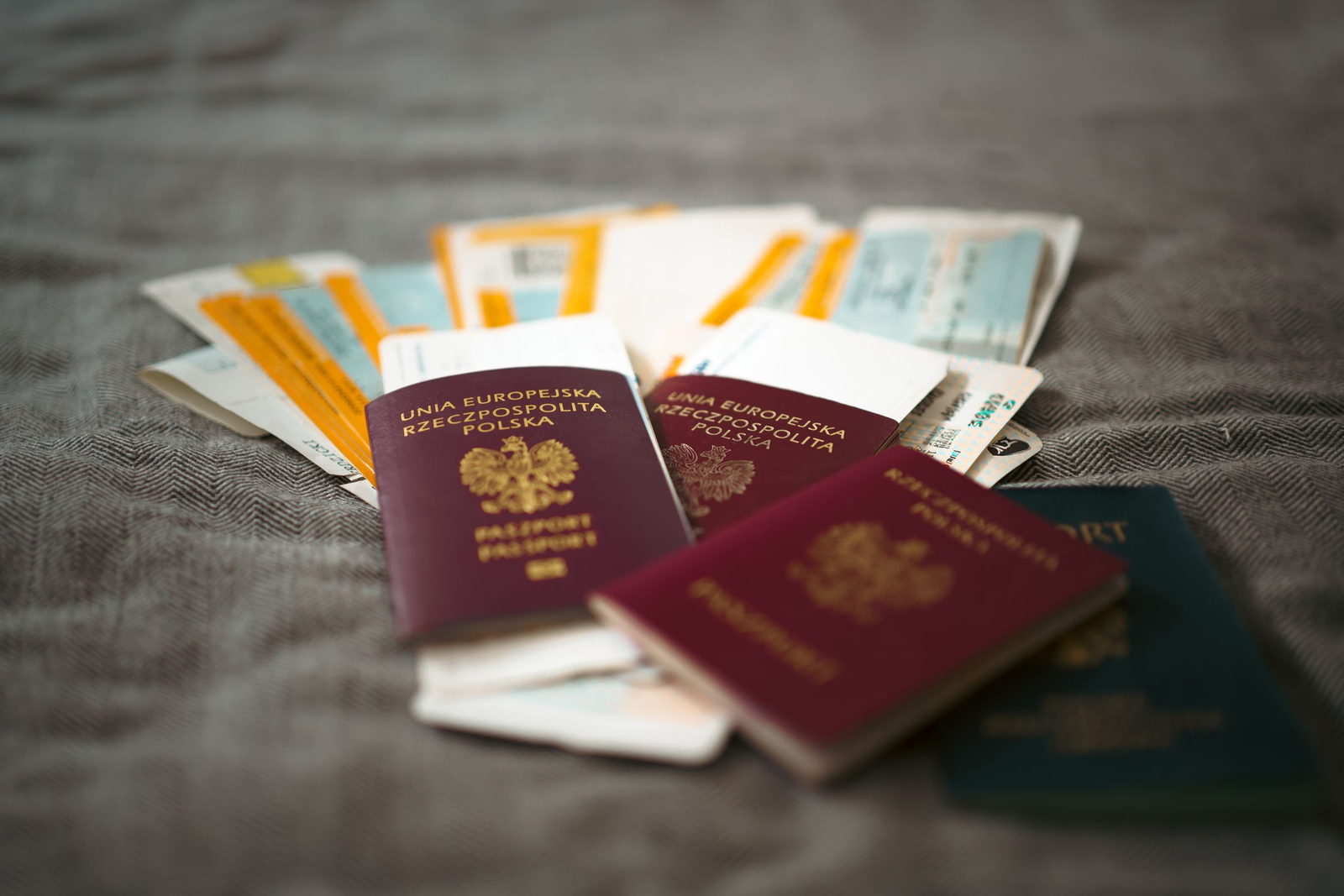 A loose pile of passports and travel documents from several countries on grey cloth